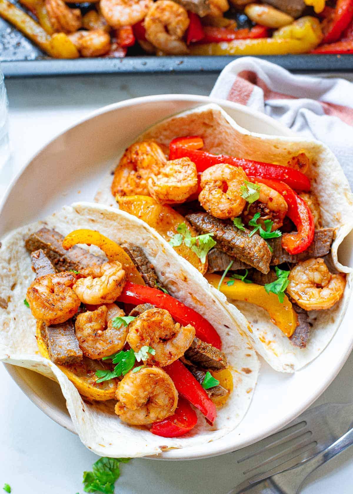 Steak and shrimp fajitas in a flour tortillas on a plate. Steak and shrimp fajitas in a flour tortillas on a plate.