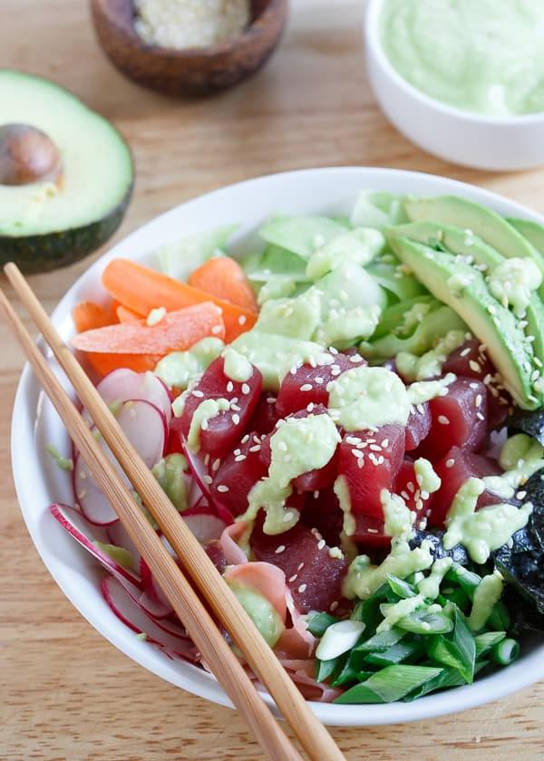 Φτιάξτε το δικό σας sushi στο σπίτι! Αυτό το γρήγορο και εύκολο sushi bowl τόνου είναι γεμάτο με ραπανάκια, καρότα, αγγούρι, φύκια και αβοκάντο, και περιχύνεται με μια πικάντικη σάλτσα αβοκάντο-wasabi.