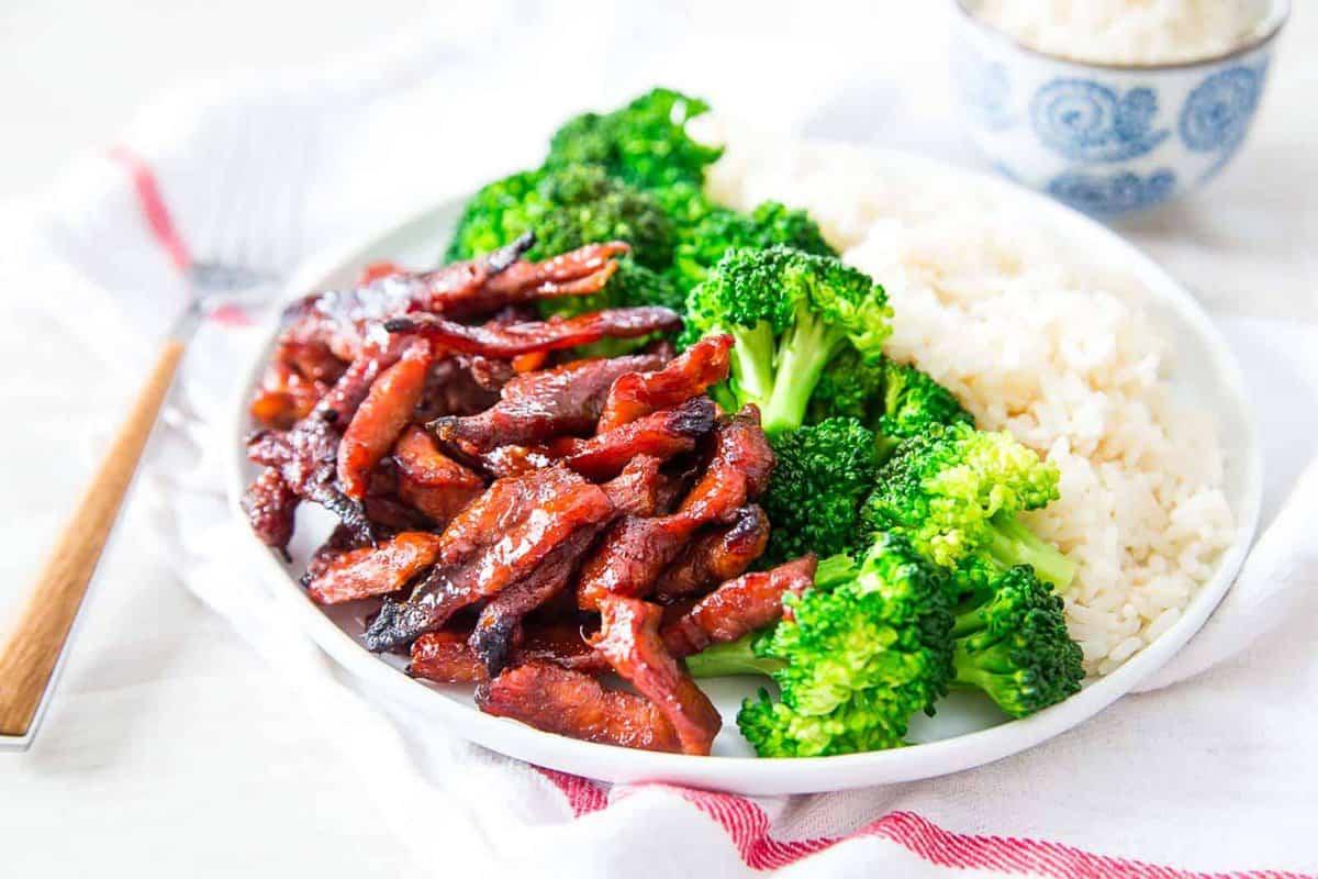 **Wok: 23 Ασιατικά Πιάτα που θα ξεπεράσουν το Takeout** 3 Σπιτικά κινέζικα χοιρινά παϊδάκια χωρίς κόκαλο με μπρόκολο και ρύζι σε ένα λευκό πιάτο.