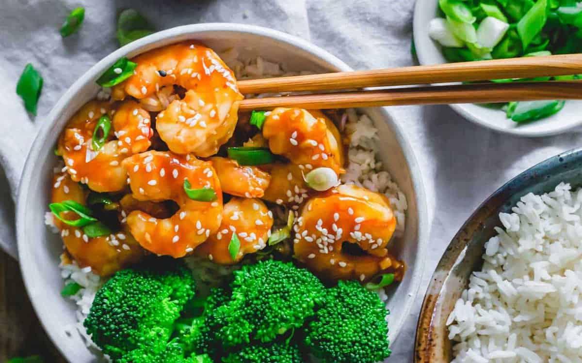 **Wok: 23 Ασιατικά Πιάτα που θα ξεπεράσουν το Takeout** 6 Σπιτικές γαρίδες General Tso με μπρόκολο και ρύζι σε ένα μπολ με chopsticks.
