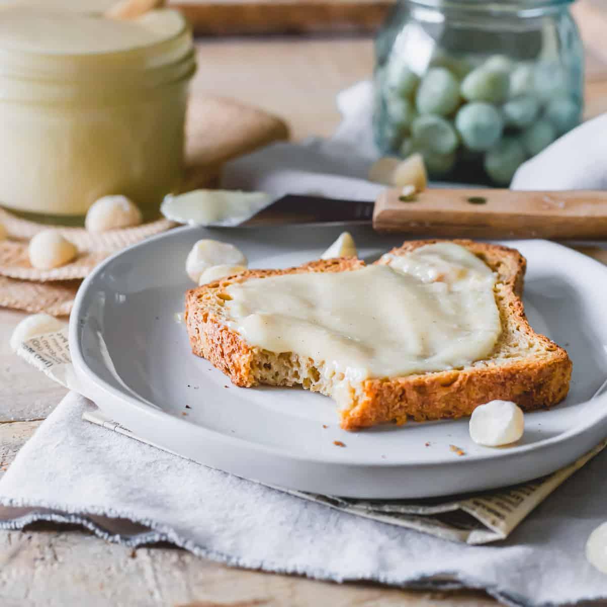 Ένα κομμάτι τοστ σε πιάτο με απλωμένο βούτυρο μακαντέμια.