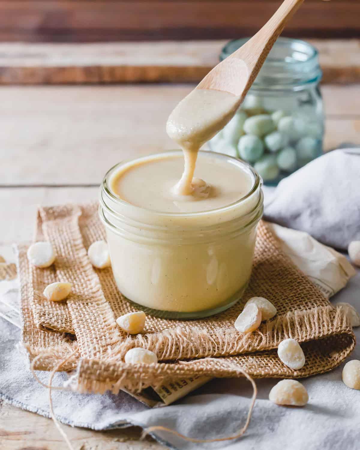 Ένα ξύλινο κουτάλι βυθίζεται σε ένα βάζο με βούτυρο μακαντέμια.