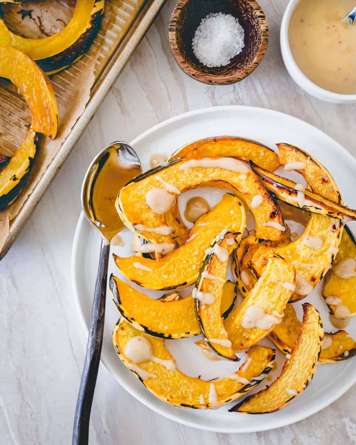 Τέλεια ψητή γλυκιά κολοκύθα sweet dumpling σε πιάτο σερβιρισμένη με σάλτσα ταχίνι σφενδάμου. Τέλεια ψητή γλυκιά κολοκύθα sweet dumpling σε πιάτο σερβιρισμένη με σάλτσα ταχίνι σφενδάμου.