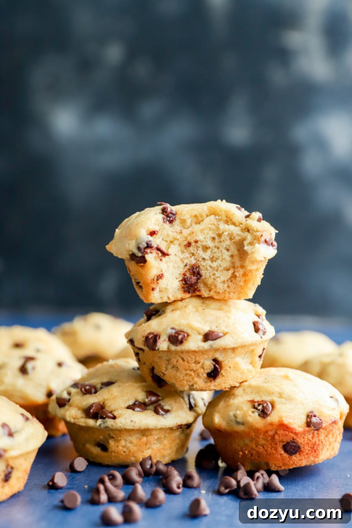 Perfectly Poppable Banana Peanut Butter Chocolate Muffins 9 Stack of mini banana peanut butter chocolate chip muffins with one having a bite taken out, showing its fluffy texture and melted chocolate chips