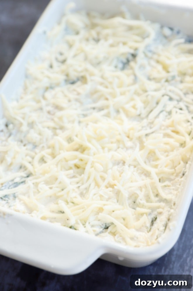 Creamy Spinach and Artichoke Goat Cheese Dip 7 Unbaked spinach and artichoke goat cheese dip mixture in a white dish, ready for the oven