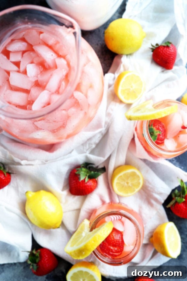 Refreshing Strawberry Vodka Lemonade 4 Three mason jars filled with pink vodka strawberry lemonade, garnished with fresh fruit, on a rustic wooden surface.