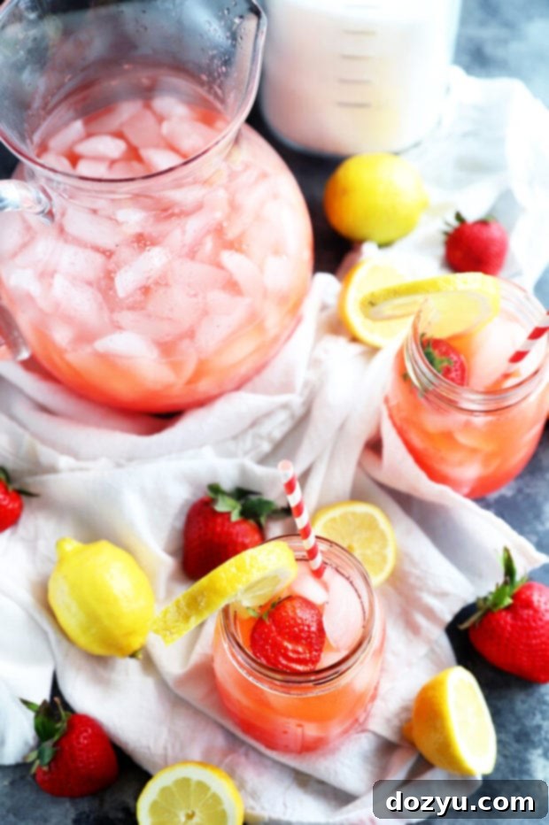 Refreshing Strawberry Vodka Lemonade 7 Several mason jars of vodka strawberry lemonade, with garnishes, arranged on a rustic wooden table, ready for serving.