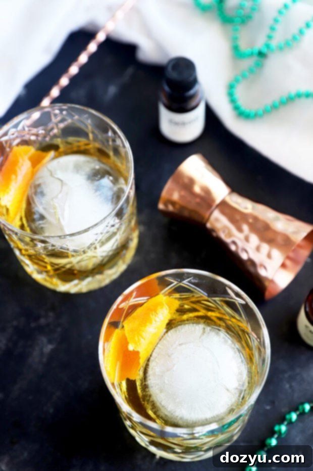 Jameson's Enduring Classic 4 Jameson Old Fashioned cocktail with an orange slice and large ice sphere, photographed with a warm, inviting light.