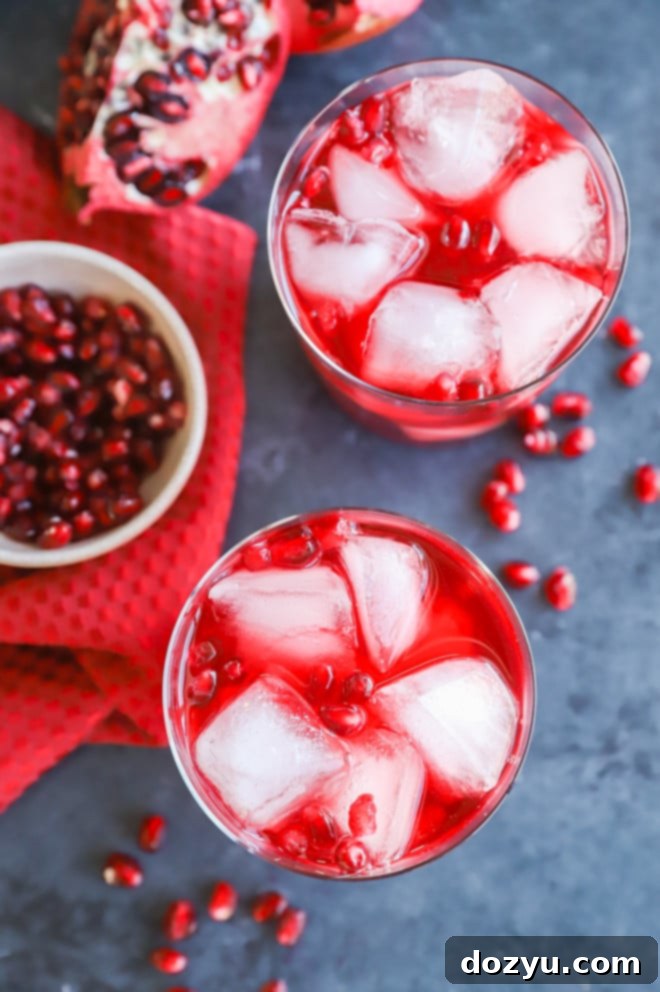 The Pomegranate Negroni 8 Three glasses of Pomegranate Negroni cocktail, each garnished with fresh pomegranate seeds, showcasing the drink's appealing color.