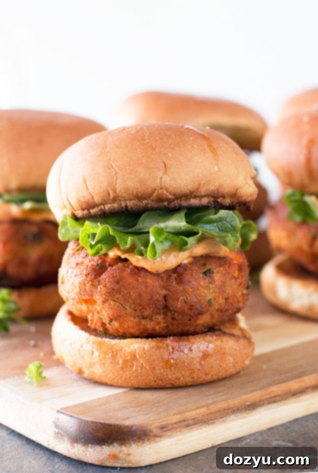 Close-up of a perfectly assembled Salmon Cake Slider with spicy mayo and fresh greens on a toasted bun