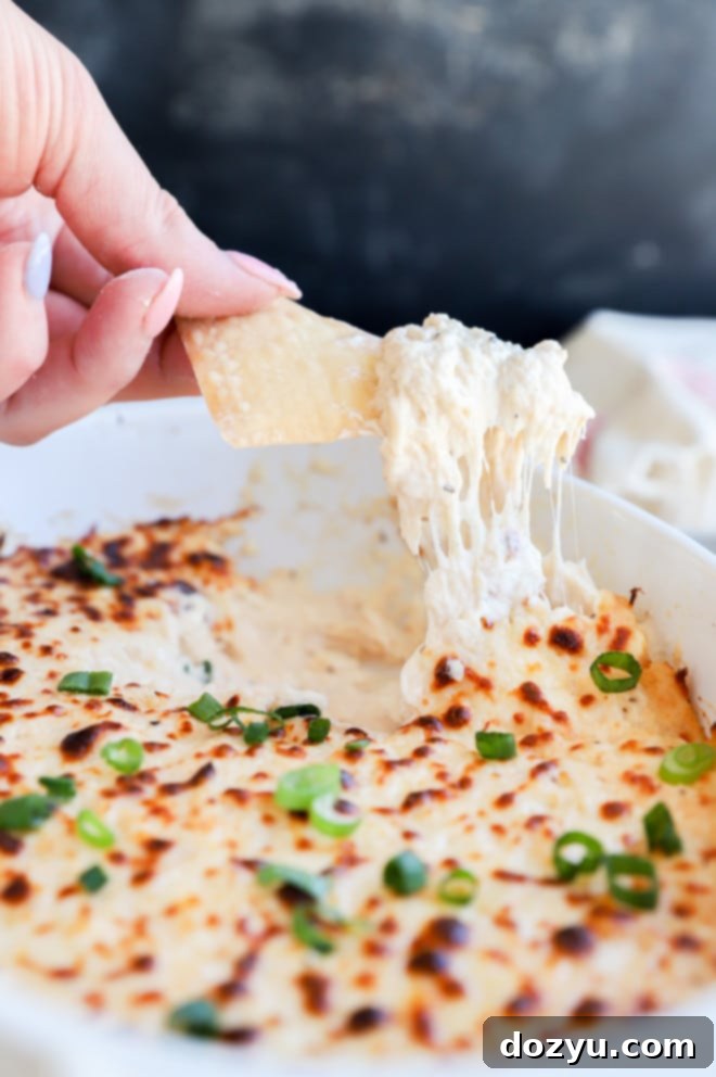 Creamy Crab Rangoon Dip with Crispy Wonton Dippers 2 Chip lifting out crab dip from casserole dish image