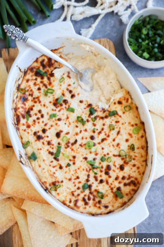 Creamy Crab Rangoon Dip with Crispy Wonton Dippers 7 Overhead image of dip in casserole dish with spoon and green onion on top
