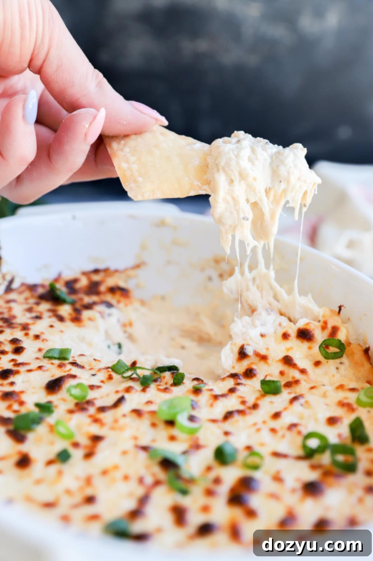 Creamy Crab Rangoon Dip with Crispy Wonton Dippers 8 Chip lifting out cheesy dip in casserole dish picture
