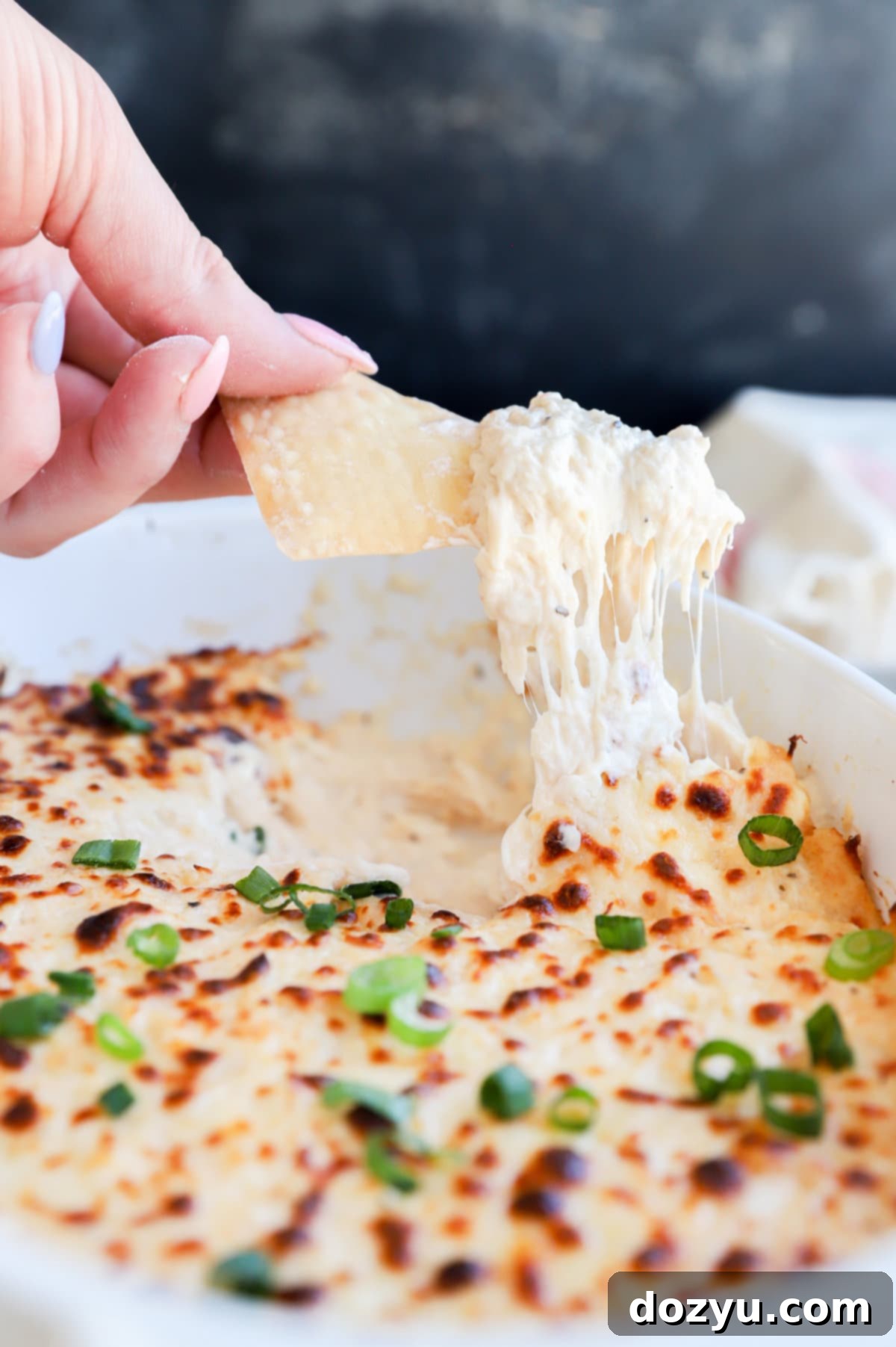 Creamy Crab Rangoon Dip with Crispy Wonton Dippers 9 Chip lifting out crab dip from casserole dish image