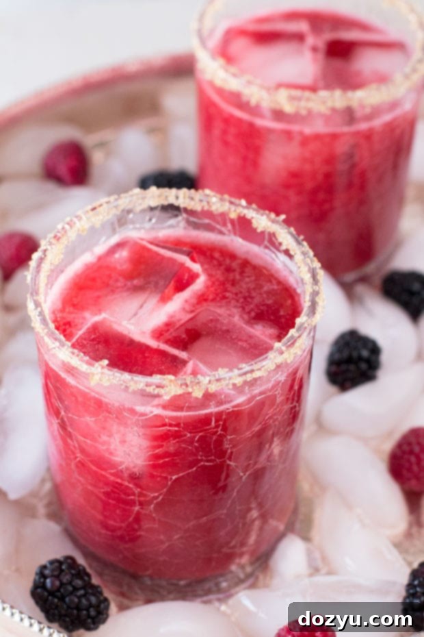 Mixed Berry Margarita served in a chilled glass with turbinado sugar rim, garnished with fresh berries.