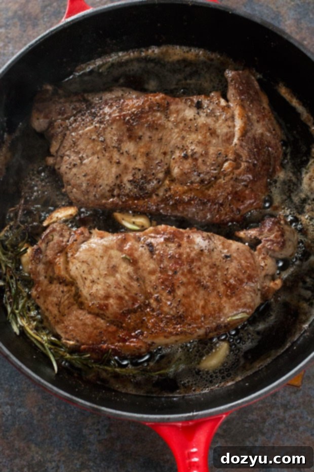 Ultimate Ribeye Perfection 3 Two perfectly seared ribeye steaks resting on a cutting board, ready to be sliced.