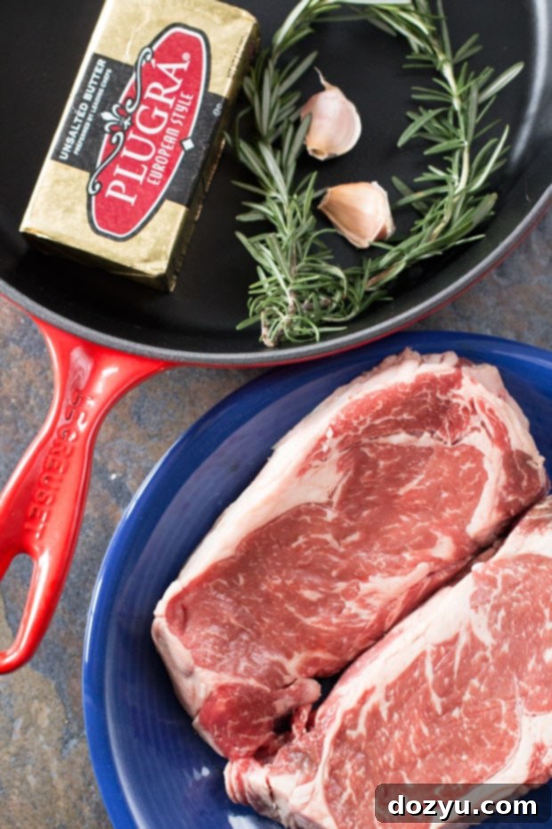 Ultimate Ribeye Perfection 4 Ingredients for The Perfect Ribeye Steak: fresh rosemary, garlic, butter, olive oil, salt, pepper, and two ribeye steaks.