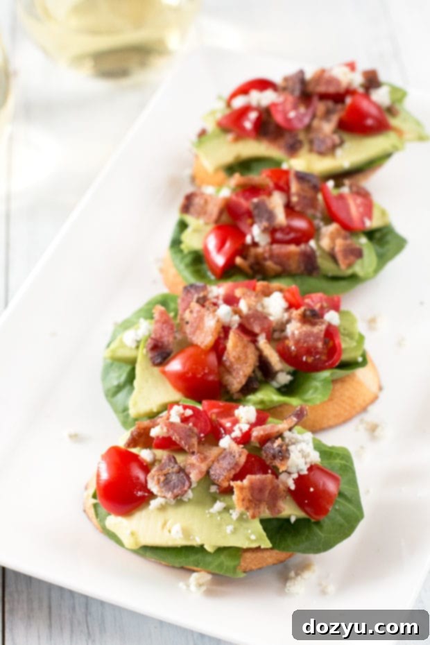 BLAT and Blue Cheese Crostini 4 Hand holding a single BLAT Blue Cheese Crostini, showcasing its layers.