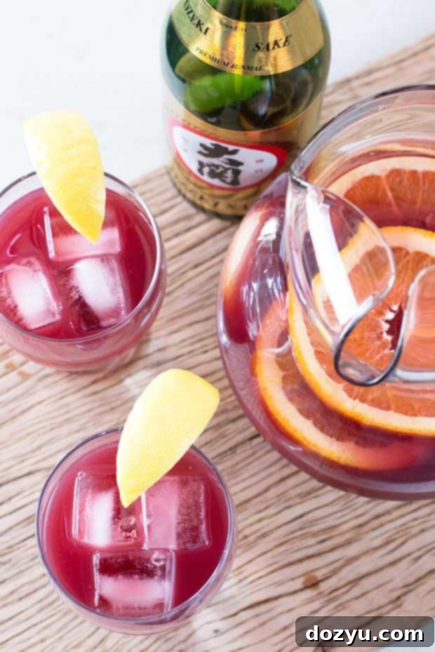 Refreshing Sake Sangria 3 Close-up of a glass of fruity Sake Sangria, showing the rich red color and citrus garnishes.