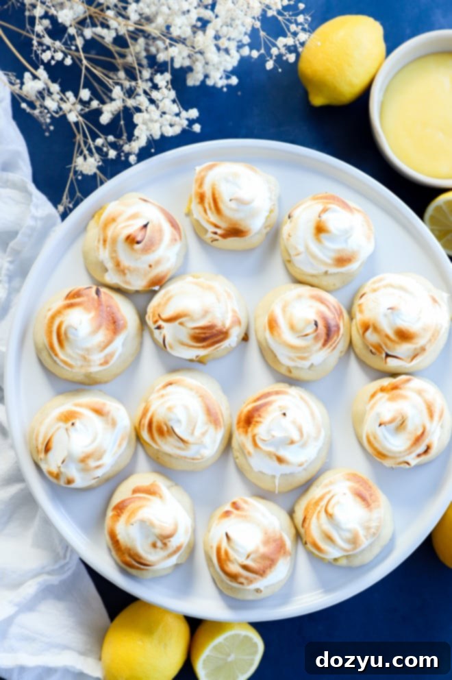 Lemon Curd Meringue Cookies 11 Lemon curd cookies on a cake plate with fresh lemons on the side, highlighting their appeal