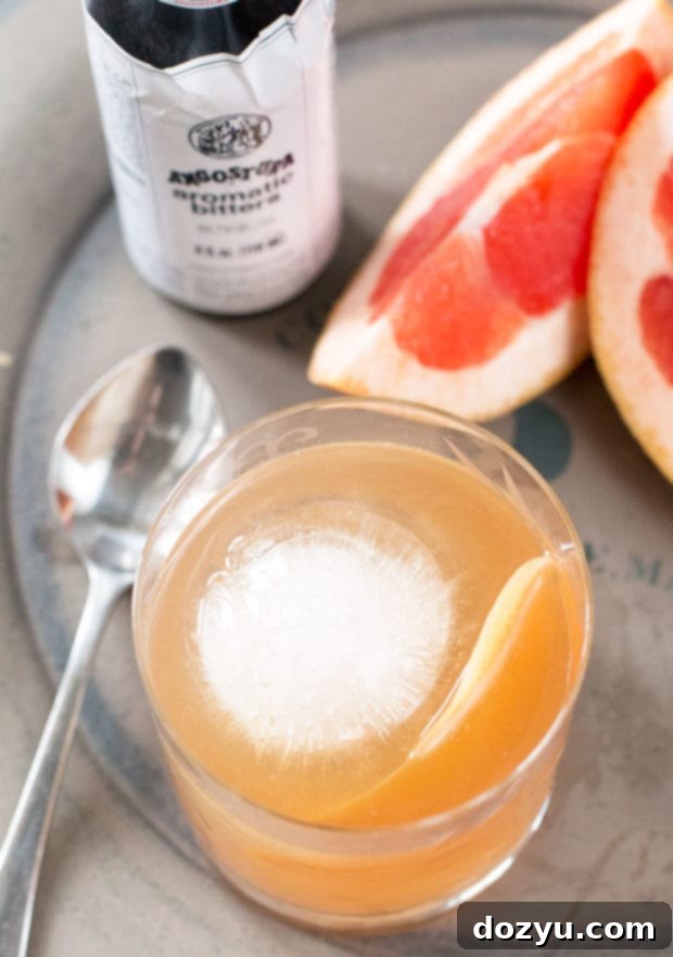 Close-up of Sparkling Grapefruit Old Fashioned with a large ice cube and grapefruit peel.