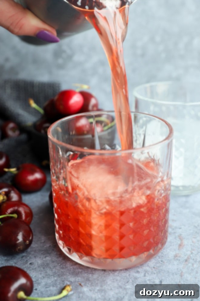 Velvet Cherry Amaretto Sour 6 Pouring red summer cocktail into glass image