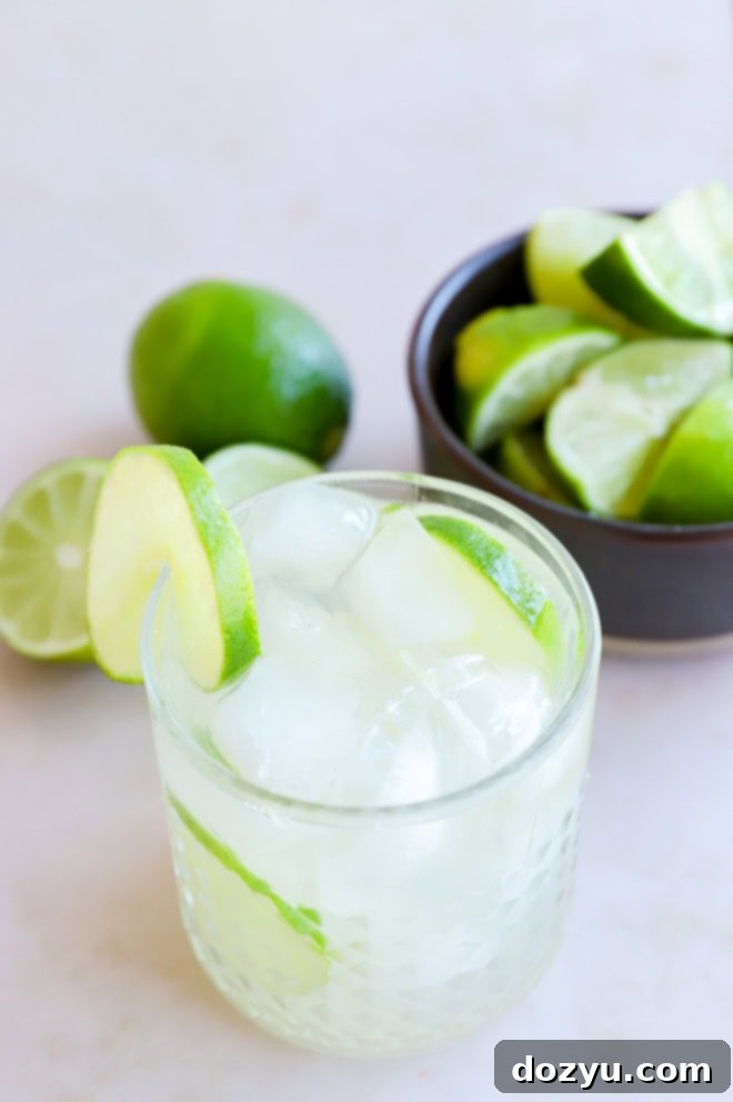 Sip of Brazil 7 caipirinha in a glass garnished with limes and a bowl of limes in the background
