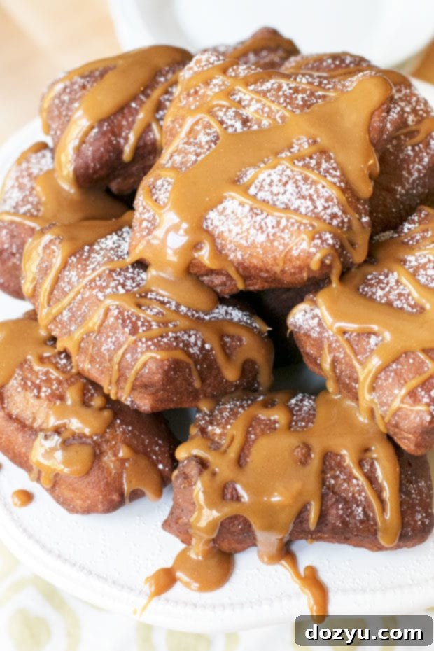 Autumn Spice Beignets with Salted Caramel Dream 2 Fluffy Pumpkin Spice Beignets with generous Salted Caramel Drizzle on a white plate, ready to be enjoyed