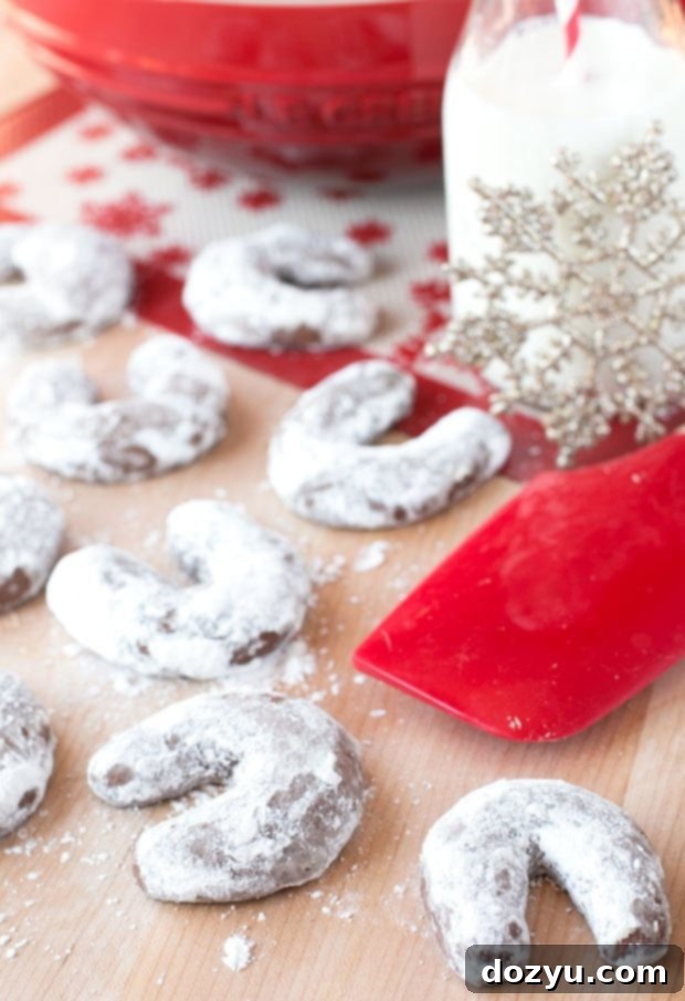 Mocha Almond Moon Cookies 2 A plate of freshly baked Almond Mocha Crescent Cookies, dusted with confectioner's sugar, against a festive holiday background. A perfect holiday treat.
