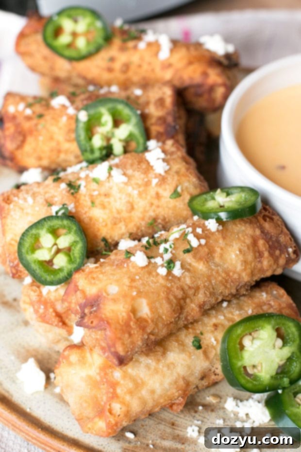 Crispy Loaded Nacho Egg Rolls served with a side of creamy queso dip, a perfect game day appetizer