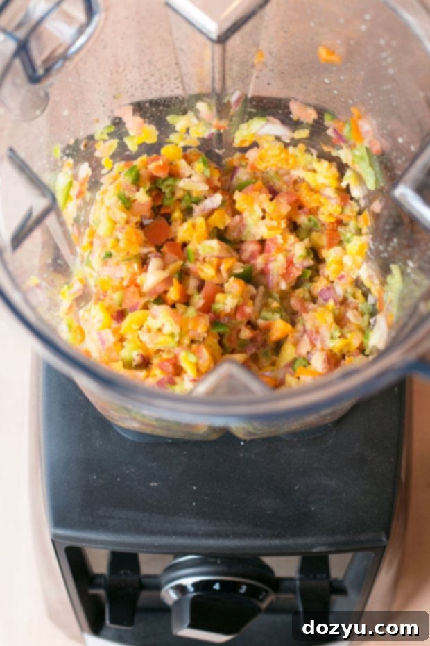 Vitamix Ascent Series Blender being used to finely dice vegetables for the nacho egg roll filling