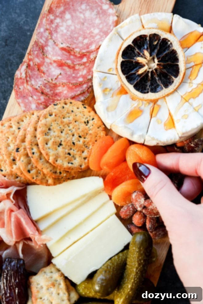 hand reaching for a dried apricot on a fully assembled easy charcuterie board