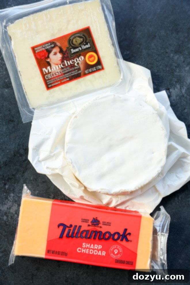 manchego, cheddar, and brie cheeses on a cutting board, ready for an easy charcuterie board