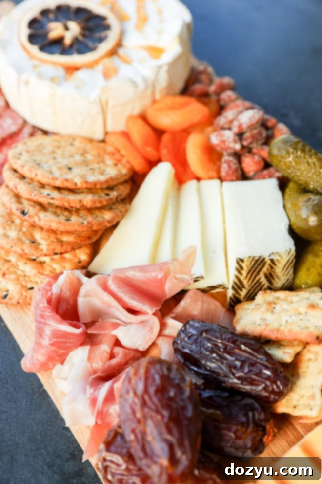 hand reaching into an easy charcuterie board to grab a dried apricot amidst meats, cheeses, and pickles