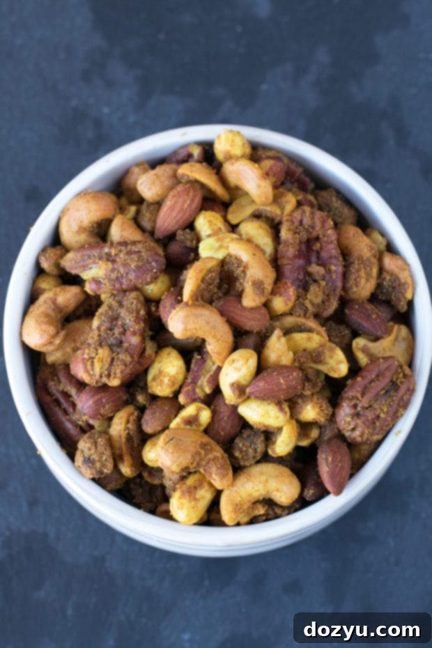 Aromatic Curried Nut Blend 5 A hand reaching into a bowl of Curried Nut Mix, emphasizing its irresistible appeal as a quick and satisfying snack.