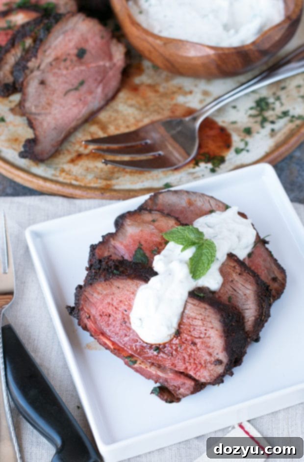 Perfectly grilled Ancho Chili Rubbed Leg of Lamb, sliced and ready to be served with cooling mint yogurt sauce.