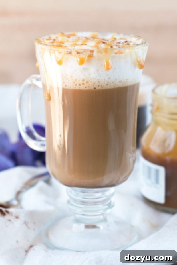 Close-up of a perfectly layered Chili Caramel Macchiato in a clear glass mug, topped with foam and caramel drizzle, ready to be enjoyed.