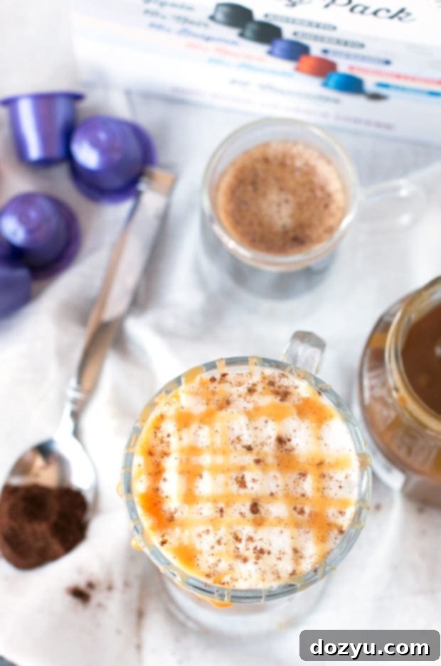 Hand holding a warm glass of homemade Chili Caramel Macchiato, showing the rich color of the coffee and steamed milk layers.