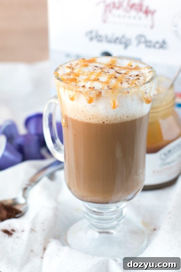 Ingredients for a homemade Chili Caramel Macchiato laid out on a clean surface: Nespresso machine, coffee capsules, almond milk, chili vanilla syrup, and caramel sauce.