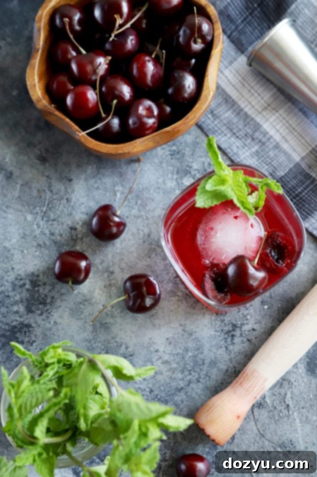 Cherry Bomb Whiskey Smash 2 Vibrant close-up photo of fresh cherries and mint leaves, ready to be muddled for a cocktail