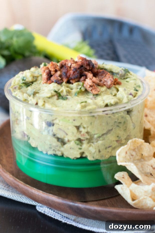 Chipotle Chorizo Guacamole in a bowl with a spoon, ready to be enjoyed with tortilla chips.