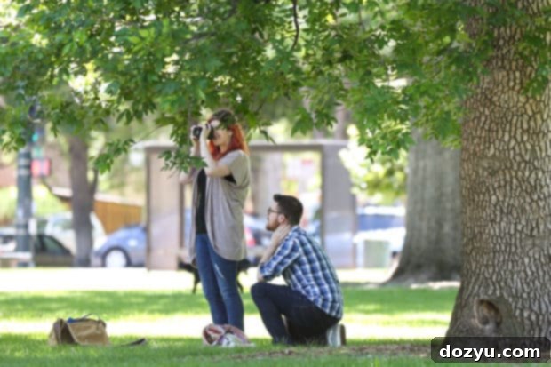 Photographer in the park, capturing the beauty before a surprise engagement