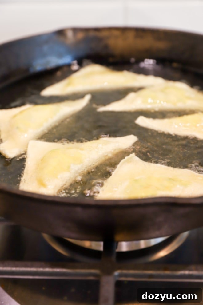 Frying jalapeno popper wontons in a cast iron skillet image