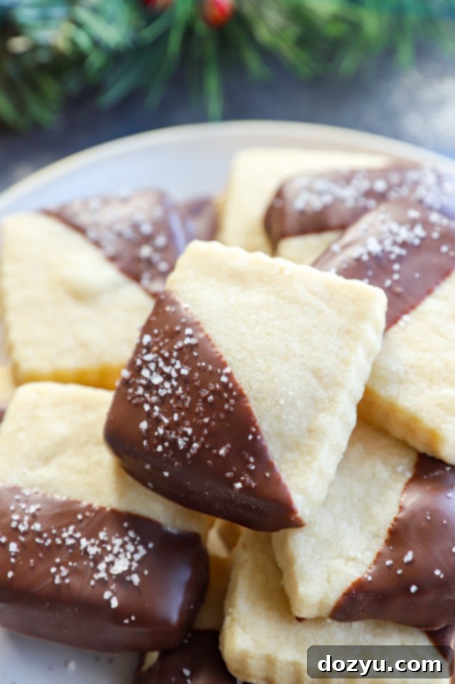 Decadent Milk Chocolate Dipped Shortbread 9 Homemade holiday treats, milk chocolate dipped shortbread cookies, garnished with chocolate and sea salt, on a wooden board.