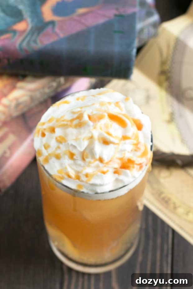 A hot Butterbeer Cocktail, beautifully presented in a clear mug with a thick layer of whipped cream and a drizzle of butterscotch, steam gently rising. This cozy drink is ideal for cold weather and Harry Potter themed events.