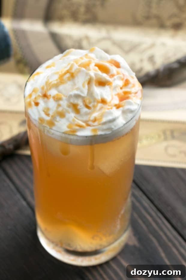A close-up of a festive Butterbeer Cocktail, garnished with creamy whipped topping and a drizzle of butterscotch syrup, ready for a magical Harry Potter party. The rich details highlight the drink's indulgent appeal.