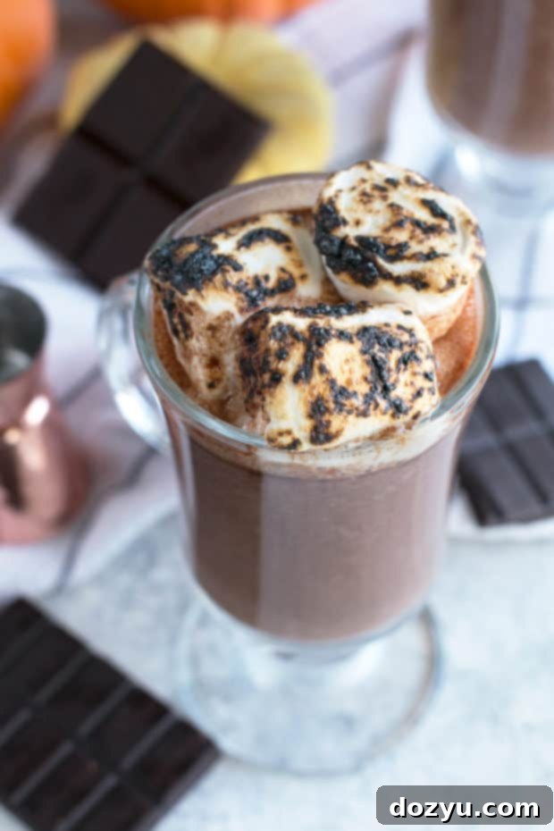 A close-up of a glass of Pumpkin Bourbon Hot Chocolate, showing the melted chocolate and smooth texture before garnishing.
