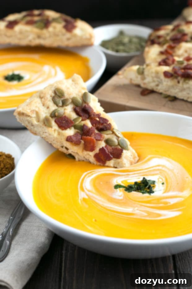 Butternut squash soup being poured into a bowl from a Vitamix blender