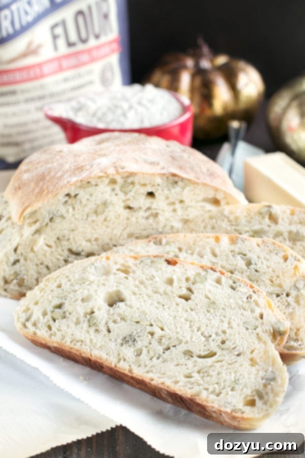 Whole loaf of Harvest Pumpkin Seed Bread on a cutting board, ready to be sliced