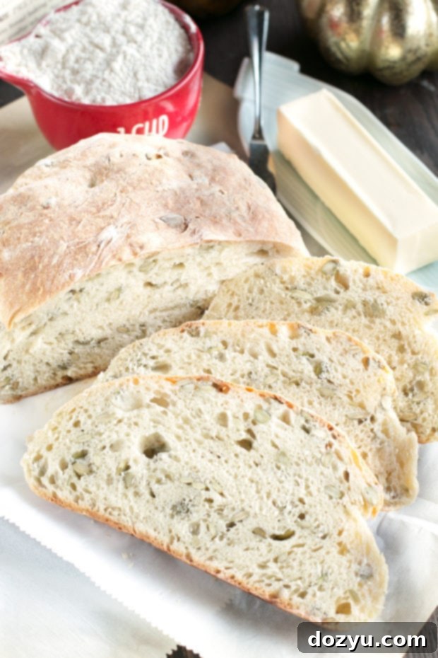 A large, rustic loaf of Harvest Pumpkin Seed Bread on a wire cooling rack